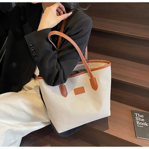 Detail of the high-quality canvas tote bag with brown leather handles and trim accents