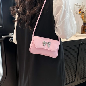 Minimalist light pink crossbody bag with a silver bow buckle and adjustable strap