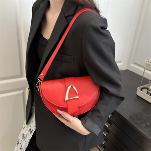 Chic red semi-circular saddle bag with golden triangle buckle on a black blazer