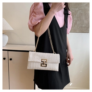 Détail du sac à bandoulière tressé beige avec une chaîne dorée et un fermoir en métal