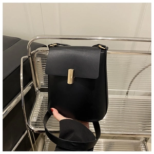 Détail du sac carré en cuir noir avec boucle dorée et base arrondie élégante