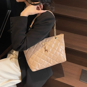 Beige quilted leather tote bag with deer pendant and chain handle shown on model