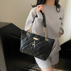 Quilted black leather tote bag with gold chain strap and deer charm shown on model