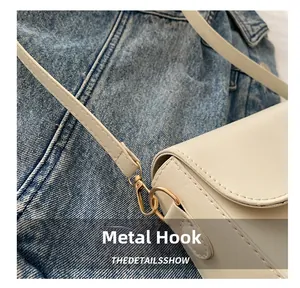 Detail of the high-quality gold hardware hook on a cream leather crossbody bag
