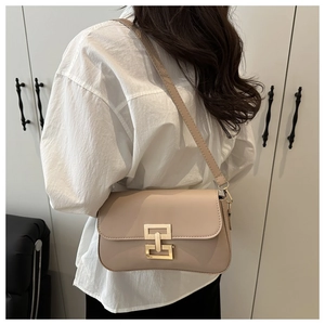 Close-up of cream leather crossbody bag featuring a unique gold geometric metal clasp