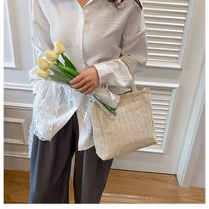 Detail einer handgewebten Stroh-Eimertasche mit Fischgrätmuster gehalten von Model