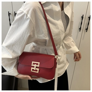 Detailed view of a red rectangular shoulder bag with a gold metal clasp on a model