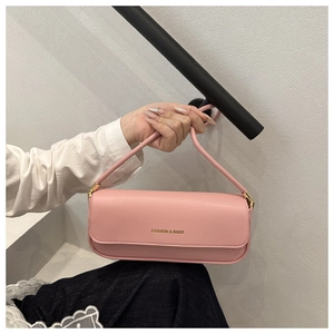 Close-up of pink leather baguette bag with gold Fashion & Bags lettering and metal hardware