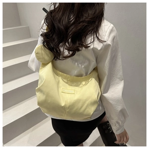 Dettaglio borsa a mezzaluna giallo chiaro con mini portamonete su scala minimalista