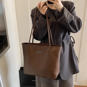 Brown lychee leather tote bag for women with minimalist design and metal logo plaque