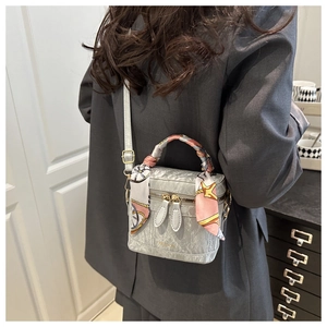 Silver square box bag with silk scarf handle detail and FASHION logo on a female model