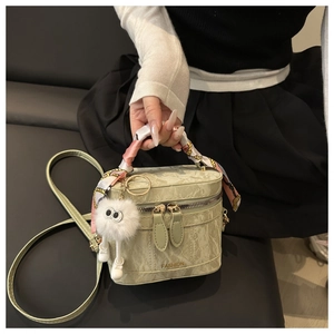 Detail of light green box bag with silk scarf handle and plush doll charm held by model