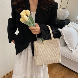 Chic beige straw tote bag with white faux leather handles for spring fashion looks