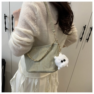 Detail of light green ruched bucket bag with gold chain and plush cat pendant