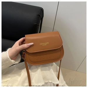 Detail of a brown saddle crossbody bag with geometric texture and golden fashion logo