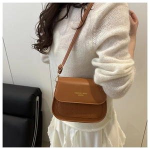 Close-up of brown leather crossbody bag with gold logo and embossed texture detail