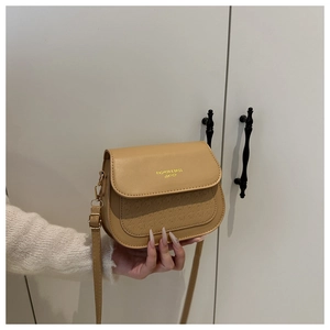 Detail of light khaki leather crossbody bag with gold lettering and embossed texture