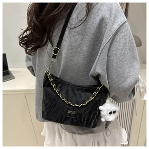 Detail of black pleated bucket bag with gold chain strap and cute plush charm pendant