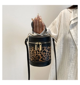 Detail of leopard print cylinder bucket bag with gold zippers and black leather trim