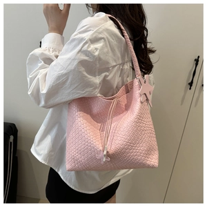 Dettaglio della borsa hobo rosa intrecciata con ciondolo a stella e tracolla coordinata