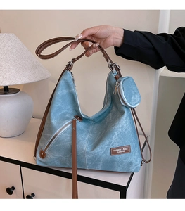 Detail of washed blue hobo tote bag with brown leather straps and small coin pouch