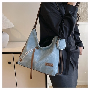Detail of light blue hobo bag with brown leather logo patch and matching coin purse