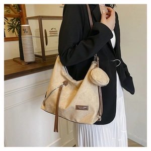 Detail of canvas tote bag with brown leather straps and small round coin purse charm