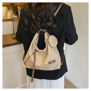 Detail of khaki canvas backpack featuring side zipper with leather pull and mini coin purse