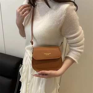 Brown leather crossbody saddle bag with geometric embossing and gold metal clasp