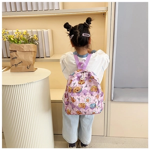 Rear view of a child wearing a purple cartoon bear print backpack in a cozy interior