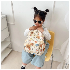 Toddler girl wearing a cream-colored cartoon bear backpack with cute plush charm detail