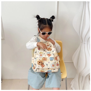 Close-up of cute cream kids backpack with cartoon bears and floral prints on a model