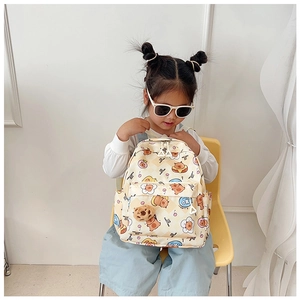 Toddler girl wearing cute cartoon bear backpack with cherry patterns in a cozy setting