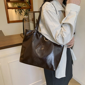 Minimalist large brown leather tote bag with glossy finish and adjustable shoulder strap