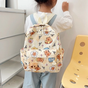Cute beige children backpack with cartoon bear prints and plush charm on model