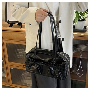 Detail of black patent leather tote bag with dual decorative bows and slim shoulder straps