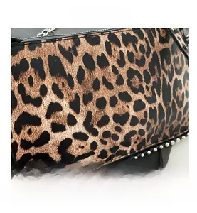 Detailed close-up of leopard print bag with silver studs and chain shoulder strap