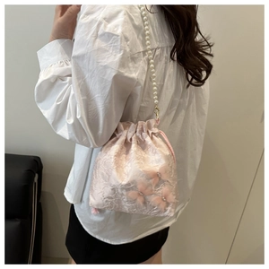 Dettaglio borsa a secchiello in raso rosa con tracolla di perle e farfalle 3D in organza