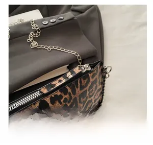 Close-up of smooth silver metal zipper and chain strap on leopard print envelope bag