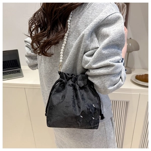 Dettaglio della borsa a secchiello nera con jacquard a rilievo e tracolla di perle