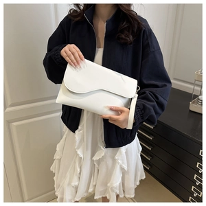 Close-up of elegant white envelope clutch bag with wavy flap design and wrist strap