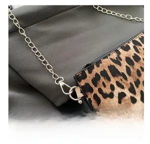 Detail of silver metal hook and chain on leopard print crossbody bag with studs