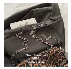 Detail of silver chain strap on leopard print crossbody bag with animal texture