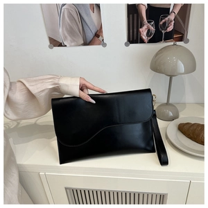 Detail of a chic black leather envelope clutch with an asymmetric curved flap design