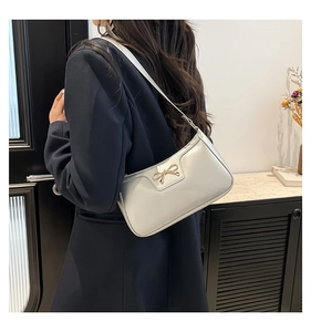 Detail of silver pearl shoulder bag featuring a decorative golden metal bow accessory