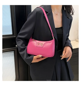 Detail of rose red shoulder bag with gold metal bow buckle and smooth PU leather