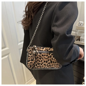 Detailed view of leopard print chain bag with silver studs and metal strap on model