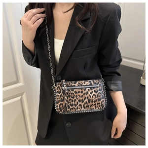 Detail showing leopard print texture, silver metal studs, and chain strap on crossbody bag