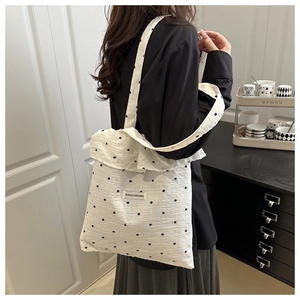 Detail of white canvas tote bag with black floral embroidery and Agogo logo tag