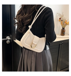 Detail of a chic cream crescent underarm bag with an elegant gold U-shaped metal buckle
